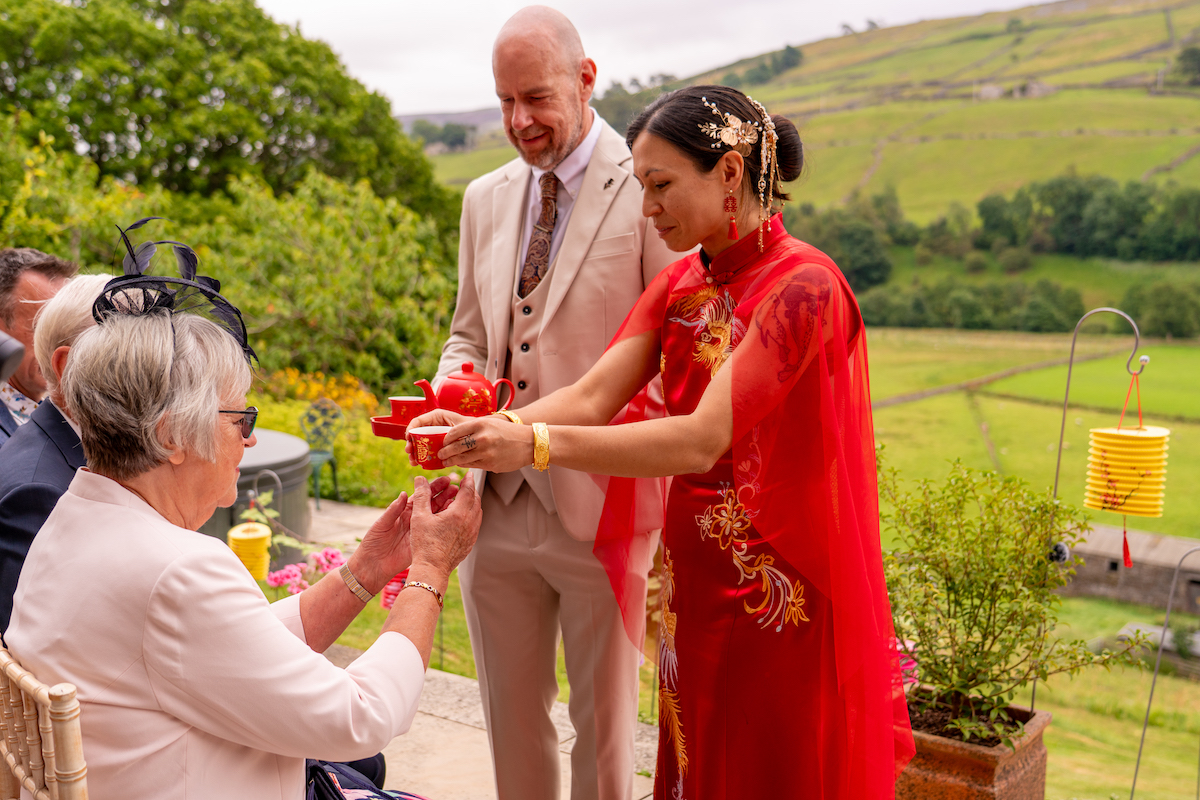 bride and groom serving tea as part of a traditional Chinese tea ceremony during the wedding ceremony